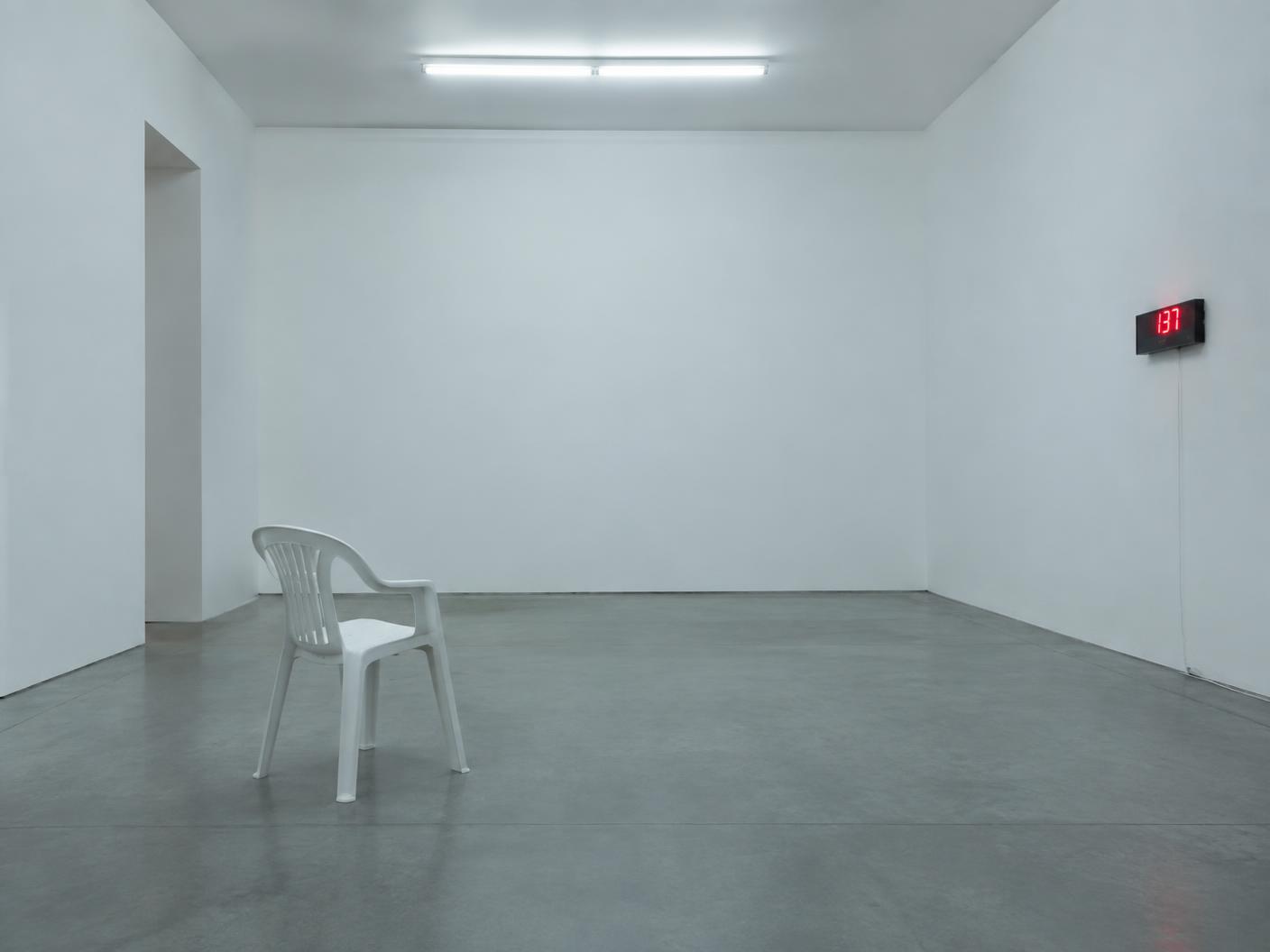 Stark empty installation room with a single chair and a number display